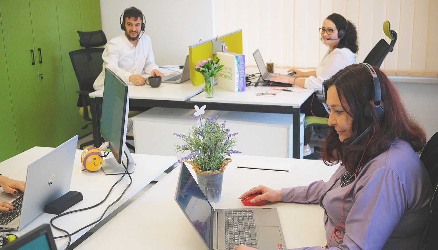 Echipa de Customer Support la birouri, purtând căști cu microfon